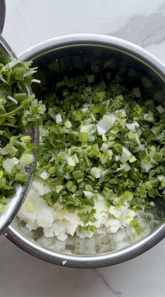 a bowl of mashed potatoes and leeks, cilantro,green onion mix